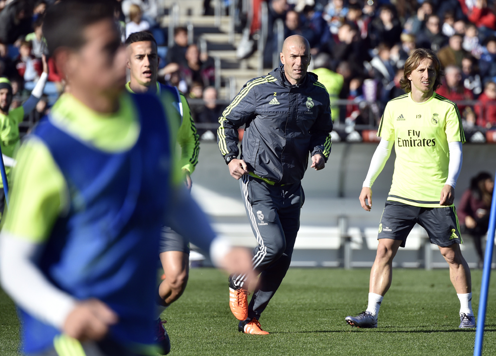 Real Madrid's new French coach Zinedine Zidane (C) runs past Real Madrid's Croatian midfielder Luka Modric (R) during his first training session as coach of Real Madrid at the Alfredo di Stefano stadium in Valdebebas, on the outskirts of Madrid, on January 5, 2016. Real Madrid legend Zinedine Zidane promised to put his "heart and soul" into managing the Spanish giants after he was sensationally named as coach following Rafael Benitez's unceremonious sacking. AFP PHOTO/ GERARD JULIEN / AFP / GERARD JULIEN