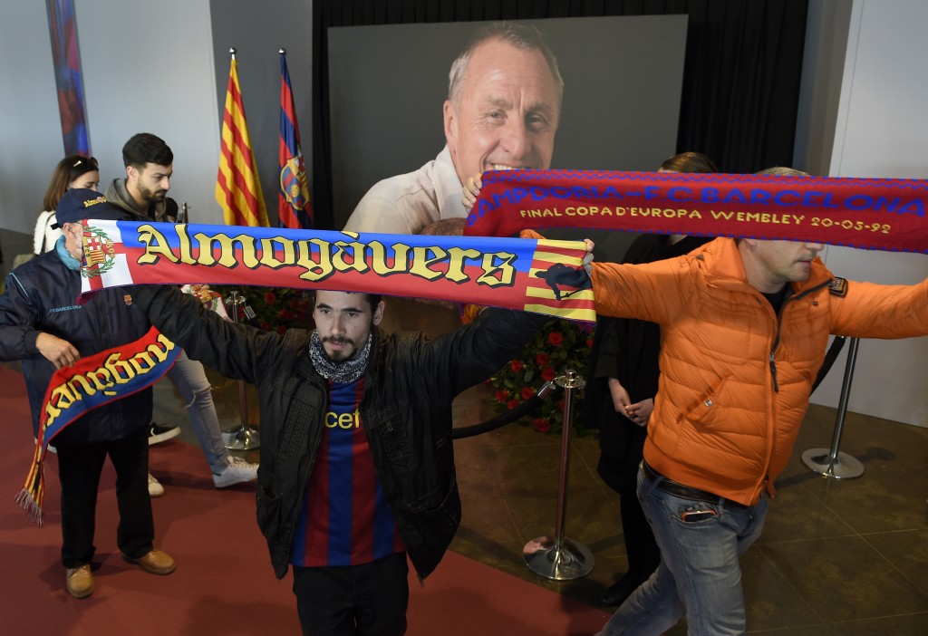 FC Barcelona football fan display scarves as they pay tribute to late Dutch football star Johan Cruyff in a special condolence area set up at Camp Nou stadium, in Barcelona on March 26, 2016. Cruyff, one of the greatest footballers of all time who dazzled with his artistry, died on March 24, 2016 at the age of 68 after losing a battle with lung cancer, prompting an avalanche of tributes from around the sports world. / AFP / LLUIS GENE