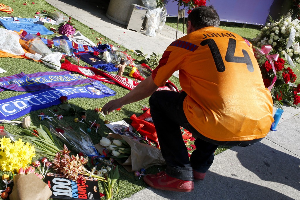 A football fan wearing a jersey of Dutch national team leaves lollipops amongst other objects as he pays tribute to late Dutch football star Johan Cruyff in a special condolence area set up at Camp Nou stadium, in Barcelona on March 26, 2016. Cruyff, one of the greatest footballers of all time who dazzled with his artistry, died on March 24, 2016 at the age of 68 after losing a battle with lung cancer, prompting an avalanche of tributes from around the sports world. / AFP / PAU BARRENA