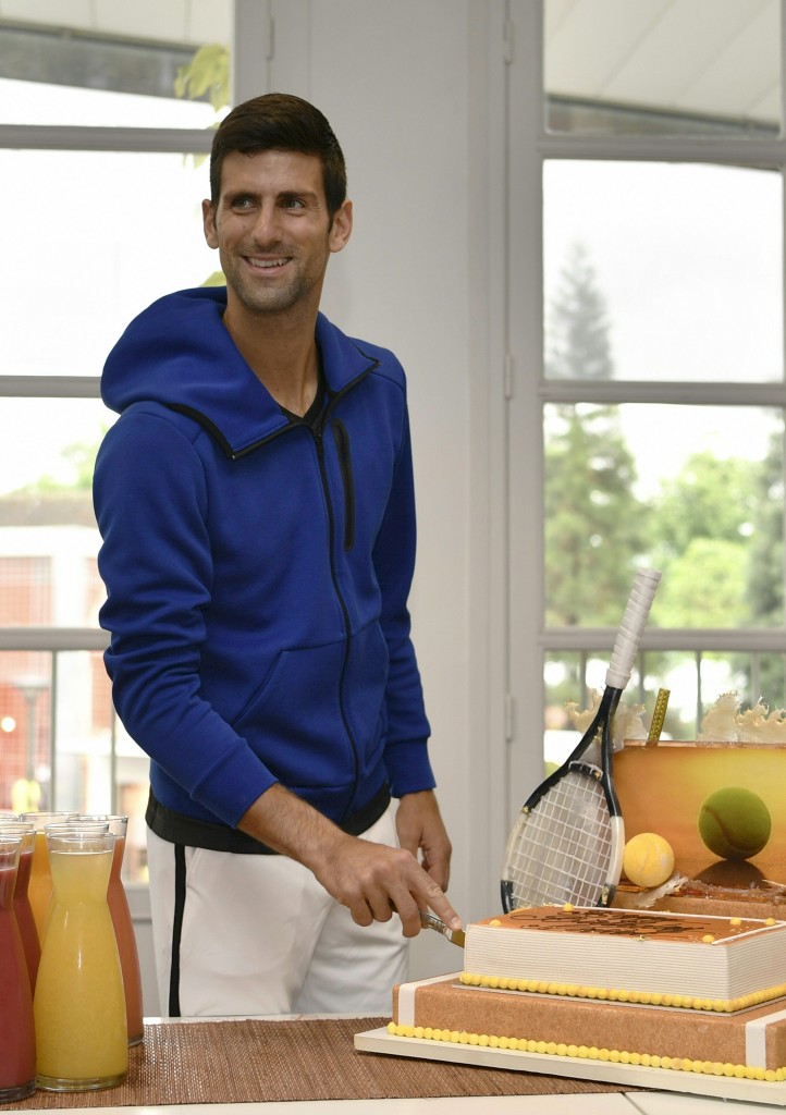 Serbia's Novak Djokovic smiles as he cuts his birthday cake at the Roland Garros 2016 French Tennis Open in Paris on May 22, 2016. / AFP PHOTO / Philippe LOPEZ